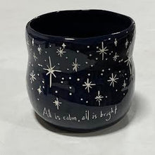 Load image into Gallery viewer, The Black Starry Planter, a dark blue ceramic piece with white stars and the phrase "All is calm, all is bright," is perfect for holiday floral arrangements and looks elegant on any light-colored surface.