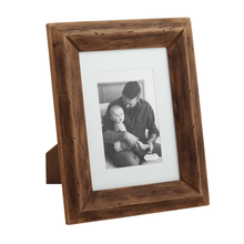 Load image into Gallery viewer, The Reclaimed Matte Wood Frame displays a black-and-white photo of an adult holding a baby. This eco-friendly frame stands upright, adding rustic charm and stylish decor to any space.