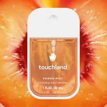 Load image into Gallery viewer, A Touchland Hand Sanitizer Mist with orange liquid is centered over vibrant, sliced peaches, creating a fresh and delicately scented backdrop for hydrated hands.