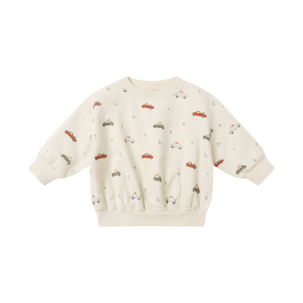 The Relaxed Fleece Sweatshirt for kids is cream, crafted from organic cotton, and features a print of small red, green, and beige cars. It has long sleeves with ribbed cuffs and hem for extra comfort.