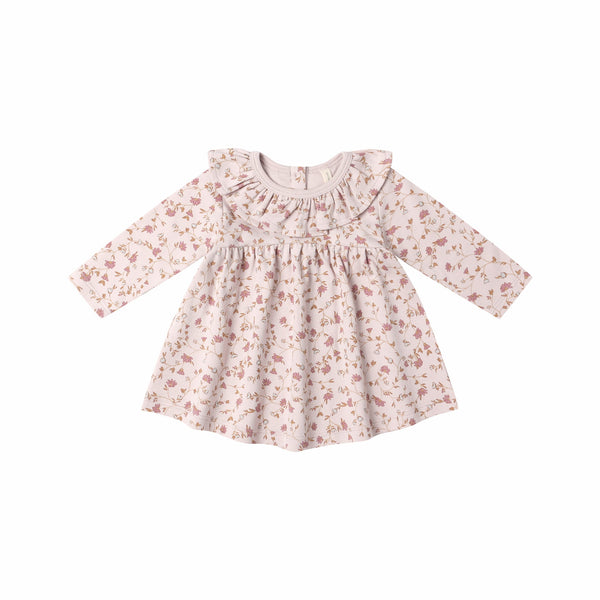The Ruffle Collar Jersey Dress is a long-sleeved, light pink baby dress featuring a ruffled collar and garden print in muted pink and brown, crafted from soft organic cotton. Displayed against a white background.