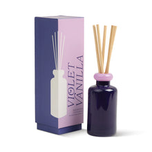 Load image into Gallery viewer, A violet Paddywax Stacked Reed Diffuser with a light pink cap and wooden reeds stands beside its matching Violet Vanilla box, which features bold purple text, a minimalist bottle illustration, and vibrant fragrance accents.