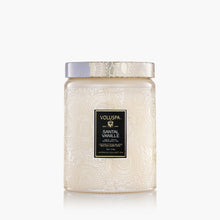 Load image into Gallery viewer, The Voluspa 18oz Glass Jar Candle features decorative white embossed glass with a matching lid. The label reads "Voluspa Santal Vanille, Japonica Collection" and the candle offers clean-burning performance with a minimalistic design.