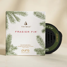 Load image into Gallery viewer, A Pura Car Diffuser Refill package with green fir branch illustrations and a round black car air freshener beside it, set against a light beige background—ideal for infusing your car with fresh, natural fragrance.