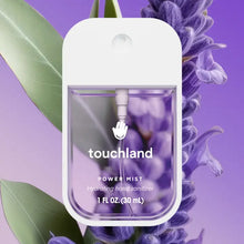 Load image into Gallery viewer, A clear bottle of Touchland Hand Sanitizer Mist is displayed before green leaves and purple flowers, set against a purple gradient background. The sanitizer liquid inside the bottle is also purple and delicately scented.