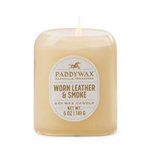 Load image into Gallery viewer, A lit 5oz Vista Candle in "Worn Leather &amp; Smoke" scent fills the room with a luxurious aroma. The simple glass jar label shows the brand, fragrance, 5 oz (141 g) weight, and Nashville, Tennessee origin.