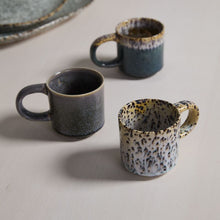 Load image into Gallery viewer, Three Starling Mug Collection stoneware mugs, featuring rounded handles and unique reactive glaze in gray, blue, and cream tones, are arranged on a light-colored surface.