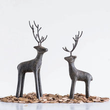 Load image into Gallery viewer, The Cast Iron Deer sculptures, featuring tall stylized antlers, stand on wood chips against a white background—an eye-catching accent for rustic home décor.